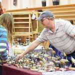 Photo by Megan Pacer/Peninsula Clarion Bill Matthews shows the wares  of Two Spirits Gallery in Wasilla to passing potential customers Friday, Nov. 25, 2016 during the Fine Arts and Craft Fair at Kenai Central High School in Kenai, Alaska. Karen Tocktoo, the gallery's owner, said this is the best fair she travels to.