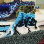 Photo by Megan Pacer/Peninsula Clarion Booties, scarves, hats and more cover a table during a meeting of the Wildwood Correctional Complex's crochet program Tuesday, Nov. 29, 2016 at the complex's pretrial building in Kenai, Alaska. The items made by inmates through the program are sent around the peninsula to be enjoyed.