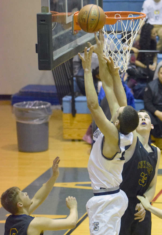 Photo by Jeff Helminiak/Peninsula Clarion Soldotna's Derek Evans challenges Ninilchik's Austin White at the rim Friday at Soldotna High School.