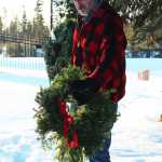 Photo by Megan Pacer/Peninsula Clarion Jim Halliday of Nikiski hangs a wreath on a steak marking the grave of a veteran Saturday, Dec. 17, 2016 at the Kenai Municipal Cemetery in Kenai, Alaska. Bob Myles, a member of the VFW and American Legion, coordinated the peninsula's first wreath ceremony through the Wreaths Across America program. Community members hung wreaths on the graves of veterans in the Kenai and Soldotna cemeteries, and Myles is working to expand the event to more peninsula cemeteries next year.