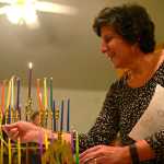 Ben Boettger/Peninsula Clarion Paula Bute of the Kenai peninsula's Briat Elohim Jewish congregation lights the first candles - from which the other candles will be lit - on a collection of menorahs during a Hanukkah celebration on Friday, Dec. 30 near Kenai. In 1983 Bute co-founded Briat Elohim with the late Gary Superman. Although the group usually meets in their own building for worship, they've traditionally celebrated Hanukkah in a member's home, according to secretary Levi Superman, Gary Superman's son.