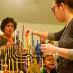 Alana Martin (right), president of the Kenai peninsula's Briat Elohim Jewish congregation, lights a menorah candle from one held by her mother, Paula Bute - who co-founded the congregation in 1983 with the late Gary Superman - during a Hanukkah celebration on Friday, Dec. 30 near Kenai. Sunday was the final day of Hanukkah.