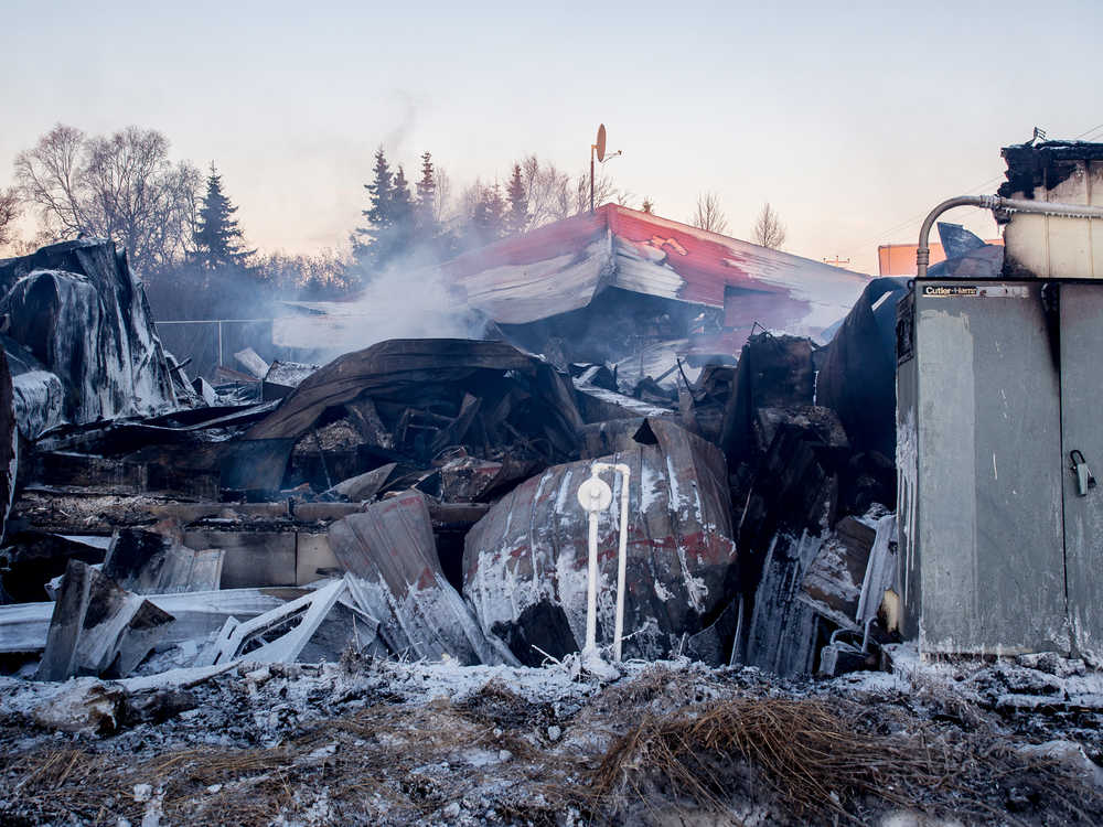 Photo courtesy Joe Kashi The remains of the Clam Shell Lodge smolder behind the former establishment's sign in this photo taken Saturday, Jan. 7, 2017 in Clam Gulch, Alaska. The building, which had not been open since 2011, burned down Friday night.