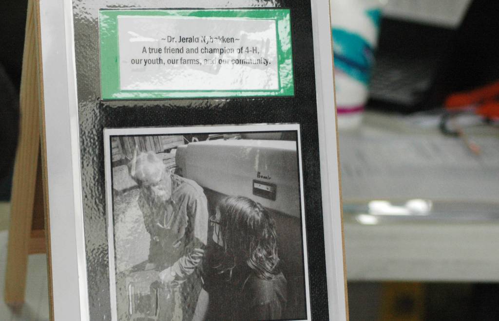 A sign noting that proceeds rom a 4-H livestock auction at the Kenai Peninsula Fair will go to support veterinarian Dr. Jerry Nybakken stands on a table at the Ninilchik Fairgrounds on Saturday, Aug. 18, 2018 in Ninilchik, Alaska. (Photo by Elizabeth Earl/Peninsula Clarion)