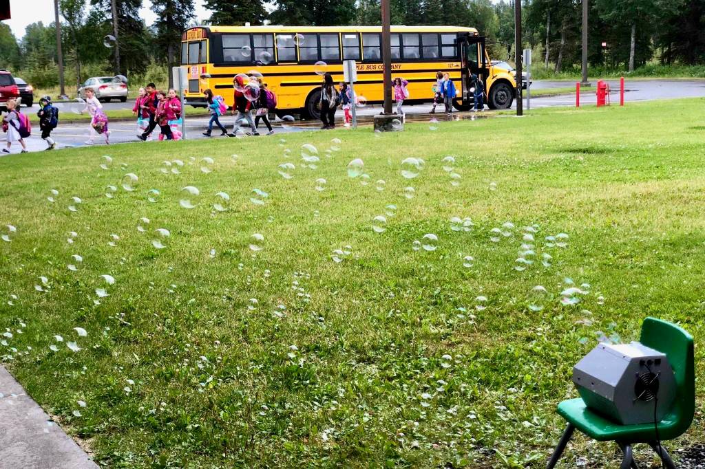 Students file out of busses on the first day of school on Tuesday, Aug. 21, 2018, at Mountain View Elementary in Kenai, Alaska. The children were welcomed by bubble machines, jazz music and Principal Kircher. (Photo by Victoria Petersen/Peninsula Clarion)