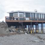 Fresh fill added on Aug. 15, 2018, replaces sand washed away last week after a series of storms and high tides eroded the beach near the Glacier Drive-In restaurant, shown here Aug. 16, 2018, on the Homer Spit, Alaska. Concrete armor rock holds the parking lot in place. The yellow plastic on the steel pilings shows where sand had been when they were installed several years ago. (Photo by Michael Armstrong/Homer News)