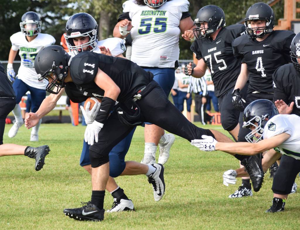 Nikiski junior Michael Eiter (11) slips through a tackle Friday against the Redington Huskies at Nikiski High School. (Photo by Joey Klecka/Peninsula Clarion)