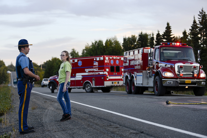 Alaska State Trooper Kyle Carson stands near the wreckage of a small plane on Saturday, August 22 near South Cohoe Loop Road.