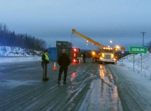 Alaska State Trooper John King talks to a motorist Monday, Dec. 15, 2015 after a truck trailer lost control on the ice and overturned at Mile 80 of the Sterling Highway. The accident occured at 4:45 a.m. Traffic was backed up half a mile for nearly an hour while a tow truck with a crane attempted to put the trailer upright. The scene was cleared by 11 a.m. The National Weather Service calls for freezing rain for Tuesday morning.