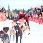 Musher Kristin Bacon rights her sled after it tipped over onto its side at the start of the Tustumena 200 Sled Dog Race on Saturday, Jan. 28, 2017 in Kasilof, Alaska. Running with Bacon's team is Crosby, one of the dogs hit and injured in the 2016 Iditarod when a man aimed his snowmachine at two teams on the trail while driving drunk. (Megan Pacer/Peninsula Clarion)
