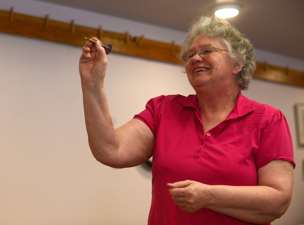 Bonnie Cain, an organizer of the 13th annual Kenai Peninsula Senior Olympics, takes aim during the Senior Olympics darts competition on Wednesday, Feb. 22, 2017 at the Soldotna Senior Center. (Ben Boettger/Peninsula Clarion). The competition was the first time Cain had played darts. &ldquo;They talked me into it,&rdquo; she said, of the friends playing with her.