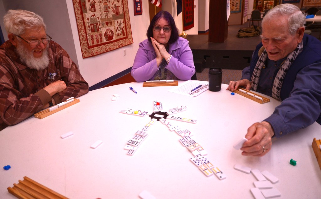 Ray Nickleson (left) and Donna Weaver watch Donna&rsquo;s husband Dick Weaver make a move in the dominoes competition of the 13th annual Kenai Peninsula Senior Olympics on Thursday, Feb. 23, 2017 at the Kenai Chamber of Commerce and Visitors Center in Kenai, Alaska.