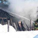 A firefighter aims water at a burning building Wednesday, March 1, 2017 at a residence on Bastien Drive in Nikiski, Alaska. The Nikiski and Kenai fire departments responded to a house fire Wednesday afternoon, in which no one was hurt. (Megan Pacer/Peninsula Clarion)