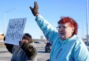 Teresa Reger (left, with sign) and Susie Stafford wave to passing cars at the annual demonstration in support of disability services by the Key Coalition advocacy group, held this year on Friday in Soldotna. Reger and Stafford are both parents of disabled adult children who receive services through the program the Key Campaign seeks to preserve. (Ben Boettger/Peninsula Clarion)