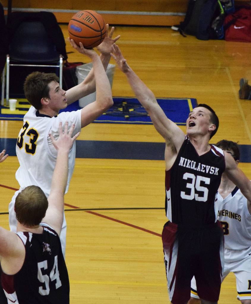 Nikolaevsk&rsquo;s Zachary Trail (35) puts a hand up on NInilchik&rsquo;s Austin White in Friday&rsquo;s Peninsula Conference boys championship game at Homer High School. (Photo by Joey Klecka/Peninsula Clarion)