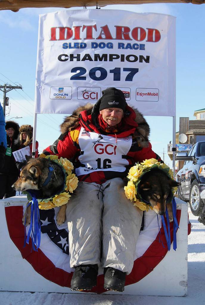 Iditarod champion Mitch Seavey of Sterling, Alaska, poses with his lead dogs Pilot, left, and Crisp under the Burled Arch after winning the 1,000-mile Iditarod Trail Sled Dog Race, in Nome, Alaska, Tuesday, March 14, 2017. Seavey won his third Iditarod Trail Sled Dog Race on Tuesday, becoming the fastest and oldest champion at age 57 and helping cement his family&rsquo;s position as mushing royalty. (AP Photo/Diana Haecker)
