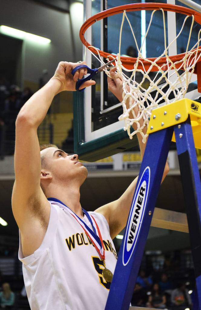 Ninilchik guard Dalton Geppert cuts down part of the basketball hoop netting following the Class 1A boys state championship Saturday at the Alaska Airlines Center in Anchorage. (Photo by Joey Klecka/Peninsula Clarion)