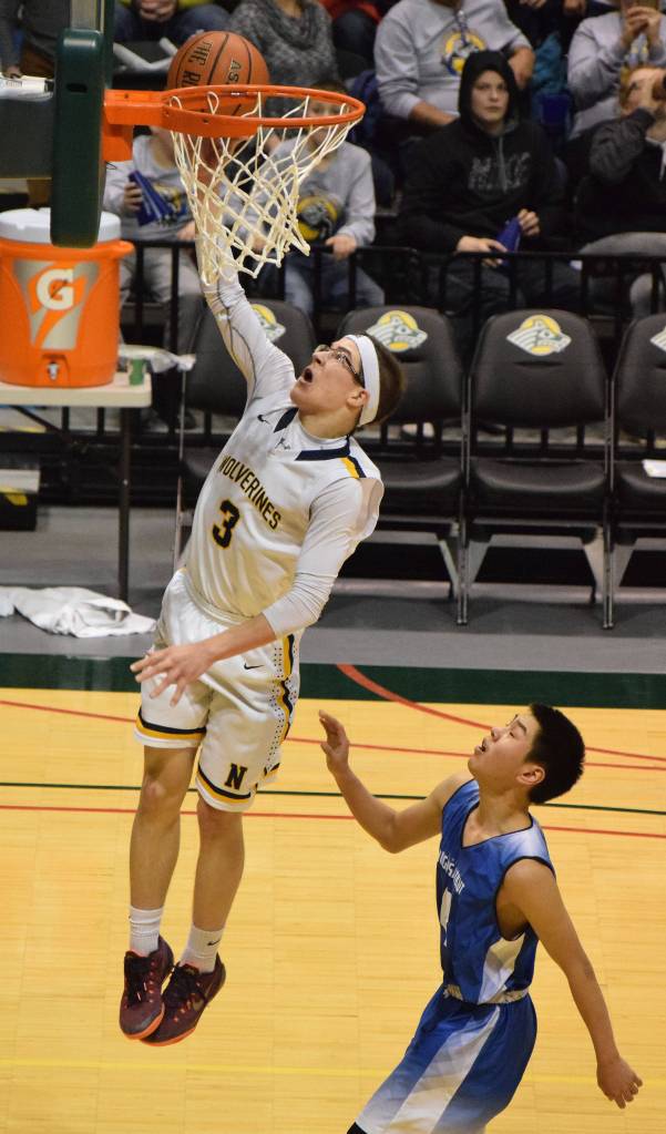 Ninilchik&rsquo;s Garrett Koch lays in a bucket with Gambell&rsquo;s Austin Appassingok in tow in theClass 1A boys state championship Saturday, March 18, 2017, at the Alaska Airlines Center in Anchorage. (Photo by Joey Klecka/Peninsula Clarion)