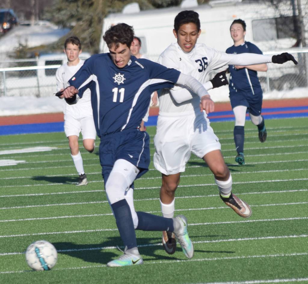 Homer&rsquo;s Charlie Menke shields Soldotna&rsquo;s Alex Montague from the ball Tuesday, April 11, 2017, at Soldotna High School. (Photo by Jeff Helminiak/Peninsula Clarion)