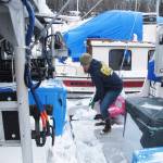 In this March 15, 2017 photo, Bonnin Jarvill, who fishes with her husband and young daughter, shovels snow from the boat that doubles as home and workplace in Juneau, Alaska. Jarvill says health care costs are a constant concern for her. (AP Photo/Becky Bohrer)