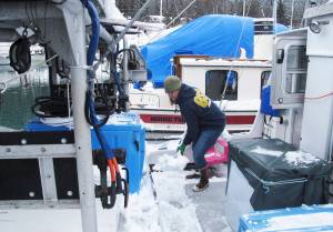 In this March 15, 2017 photo, Bonnin Jarvill, who fishes with her husband and young daughter, shovels snow from the boat that doubles as home and workplace in Juneau, Alaska. Jarvill says health care costs are a constant concern for her. (AP Photo/Becky Bohrer)