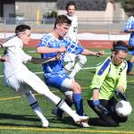 Palmer goalkeeper Caden Brown (right) wards off an offensive attack from Kenai Central&rsquo;s Kalvin Daniels (left) while teammate Makeehan Knittle puts up a block, Saturday at Ed Hollier Field in Kenai. (Photo by Joey Klecka/Peninsula Clarion)