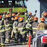 Students from Western Alaska schools participating in Excel Alaska&rsquo;s Camp Kick Ash thrust their hands into the air after their instructor, Bryan Crisp of the Nikiski Fire Department, asks who would like to be the first to break a glass car window, on Thursday, April 20, 2017 at Nikiski Fire Station 2 in Nikiski, Alaska. The students got schooled in basic firefighting techniques during the week-long camp hosted at the fire department. (Megan Pacer/Peninsula Clarion)