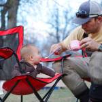 In this March 19 photo, Josh Peterson, feeds his daughter, Miriam, at a campground near Sundance, Wyo. Taking children outside is a must, say outdoorsy parents, both for the kids and the adults. (Christene Peterson /The Casper Star-Tribune via AP)