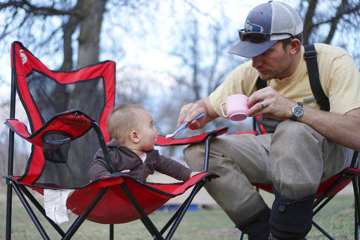 In this March 19 photo, Josh Peterson, feeds his daughter, Miriam, at a campground near Sundance, Wyo. Taking children outside is a must, say outdoorsy parents, both for the kids and the adults. (Christene Peterson /The Casper Star-Tribune via AP)
