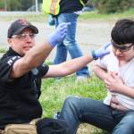A member of the Nikiski Fire Department directs his fellow teammates while tending to the fake injuries of 14-year-old Petie Deveer during a simulated meth lab explosion Saturday, May 20, 2017 at the North Peninsula Recreation Center in Nikiski, Alaska. Several members of Kenai Peninsula law enforcement agencies and emergency medical service organizations have been taking a multi-day course focused on working together on violent calls from Las Vegas-based JTM Training Group, which culminated in Saturday&rsquo;s emergency drills. (Megan Pacer/Peninsula Clarion)