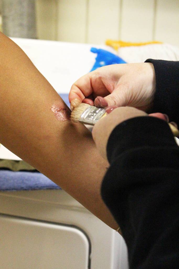 Heather Westrum, lead affects artist with Las Vegas-based JTM Training Group, applies makeup that will eventually become a gunshot wound to 19-year-old Javon Pamplin&rsquo;s arm moments before he takes part in a simulated active shooter scenario Saturday, May 20, 2017 at the North Peninsula Recreation Center in Nikiski, Alaska. The training group comes to Alaska annually to provide a course that helps first responders and members of law enforcement work together more efficiently during calls that turn violent. (Megan Pacer/Peninsula Clarion)