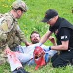 Arizona resident Nathan Lieber, a trauma amputee actor, looks at his own fake injuries casued by a simulated meth lab explosion while two local law enforement and emergency medical services personnel tend to him during a training drill Saturday, May 20, 2017 at the North Peninsula Recreation Center in Nikiski, Alaska. Lieber works for JTM Training Group, based out of Las Vegas, which travels to Alaska every year to conduct several multi-day training courses for members of law enforcement, corrections and medical first responders to practice working together in emergencies that turn violent. (Megan Pacer/Peninsula Clarion)