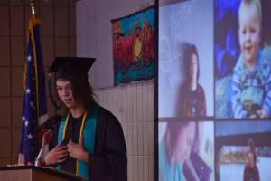 Flanked by his past portraits, River City Academy graduate Morgan Shepherd speaks to his eleven peers in River City&rsquo;s class of 2017 during the school&rsquo;s graduation ceremony on Wednesday, May 24, 2017 at the Soldotna Regional Sports Complex in Soldotna, Alaska. All the graduates gave speeches at the ceremony, introduced by principal Dawn Edwards-Smith, who compared each one to a literary or cinematic hero.