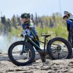 Lukas Renner, 8, gets off his bike to walk through the soft sand before the final hill to the finish Monday, May 29, 2017, at the Mouth to Mouth Wild Run and Ride. Many riders were calling that soft sand and hill the toughest part of the course. (Photo by Jeff Helminiak/Peninsula Clarion)