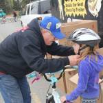 Retired CES Fire Marshal Gary Hale properly fits a bike helmet at Redoubt Bike Rodeo.