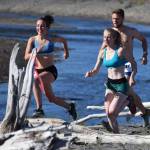 From left to right, Riana Boonstra, Alex Bergholtz and Josiah Martin leap several beached logs Saturday at the third annual Clam Scramble Mud Run in Ninilchik. (Photo by Joey Klecka/Peninsula Clarion)