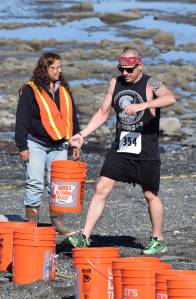Joshua Holley (354) carries a sand-filled bucket along the beach Saturday at the third annual Clam Scramble Mud Run in Ninilchik. (Photo by Joey Klecka/Peninsula Clarion)