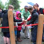 The winners of the Pathways of Poetry contest cut a ribbon opening a celebratory walk down the trail where their poems are displayed on signs Saturday, July 1, 2017 at Kenai Municipal Park in Kenai, Alaska. A panel of judges chose 12 winners out of 86 student participants, who submitted poems about nature. Scanning the codes on the signs brings up a recording of the authors reading their pieces. (Photo by Megan Pacer/Peninsula Clarion)