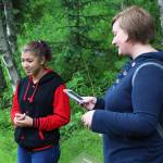 Ryanna Thurman, right, finishes listening to an oration of Kenai Central High School student Kassandra Renfrow&rsquo;s poem, one of the winning entries to the Pathways of Poetry contest, Saturday, July 1, 2017 on the trail at Kenai Municipal Park in Kenai, Alaska. A panel of judges chose 12 winners out of 86 student participants, whose poems about nature are placed on signs along the trail. Scanning the codes on the signs brings up a recording of the authors reading their pieces. (Photo by Megan Pacer/Peninsula Clarion)