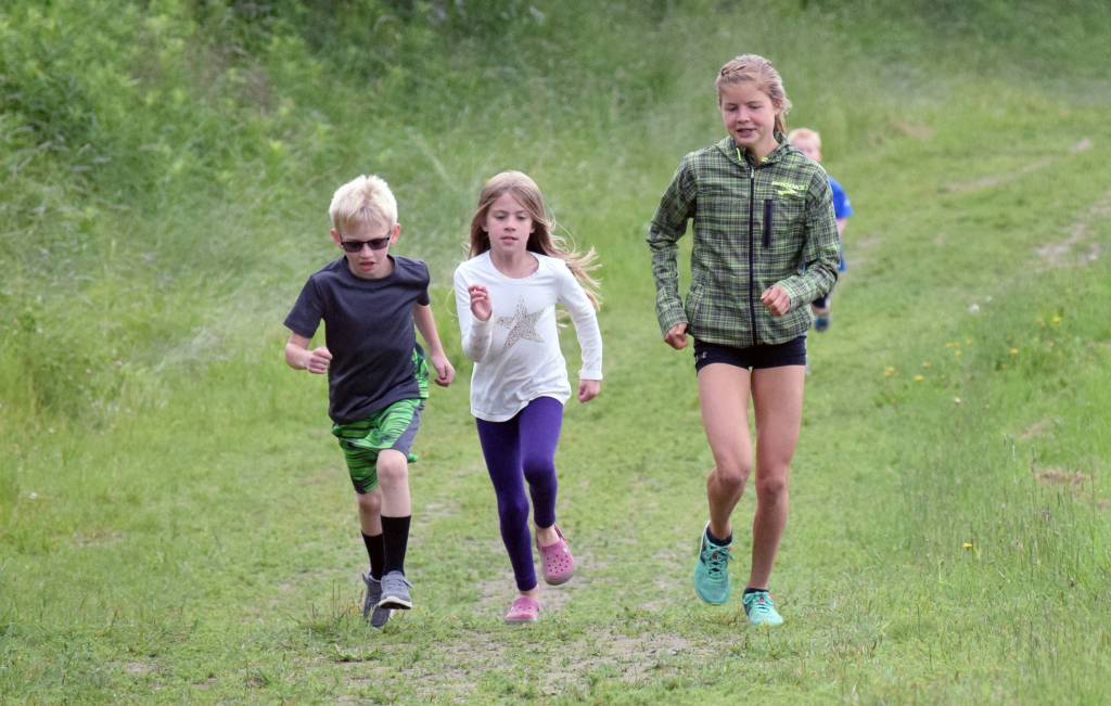 Allie Ostrander paces Corbyn Crisp, 7, of Nikiski, Esther Lattin, 8, of Soldotna, and all the other kids runners up the hill at the start of the one-kilometer kids race Wednesday, July 19, 2017, at the Salmon Run Series at Tsalteshi Trails. Crisp said he has won each of the three races this season. (Photo by Jeff Helminiak/Peninsula Clarion)