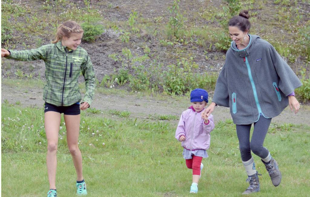 Allie Ostrander points Tessa Rhyner, currently living in South Korea but originally from Kenai, and daughter Atlas Tilly, 3, to the finish line of the kids one-kilometer race at the Salmon Run Series on Wednesday, July 19, 2017, at Tsalteshi Trails. (Photo by Jeff Helminiak/Peninsula Clarion)