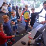 Kenai children&rsquo;s librarian James Adcox (right) links hands with local students to create a human electrical circuit during a demonstration of the Kenai Community Library&rsquo;s new Raspberry Pi computers and Makey Makey input devices on Monday, July 24, 2017 in Kenai, Alaska. When Adcox completes the circuit by clapping his neighbor&rsquo;s hand, it triggers a program &mdash; written in the educational coding language Scratch &mdash; to change the outfit of a cartoon cat displayed on the computer monitor. The demo helped kick off the Kenai Library&rsquo;s new youth club for beginning computer science using Raspberry Pi miniature computers. (Ben Boettger/Peninsula Clarion).