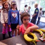 Tayla Cole plays with a program called &ldquo;Banana Piano,&rdquo; running on a Raspberry Pi computer, as Taylor Crista (right) and Amy Sevast look on during a Raspberry Pi demonstration on Monday, July 24, 2017 at the Kenai Public Library in Kenai, Alaska. The program uses the fruit&rsquo;s electrical conductivity, and the conductivity of human skin, to make bannas &mdash; wired through an input device called Makey Makey &mdash; produce digital tones when touched. Kenai Library intern Kianna Steadman used the Bannana Piano and other inventions to introduce the Kenai Library&rsquo;s twelve Raspberry Pi computers, which will be the subject of three workshops at the library next week, and a club that will meet weekly thereafter. (Photo by Ben Boettger/Peninsula Clarion)