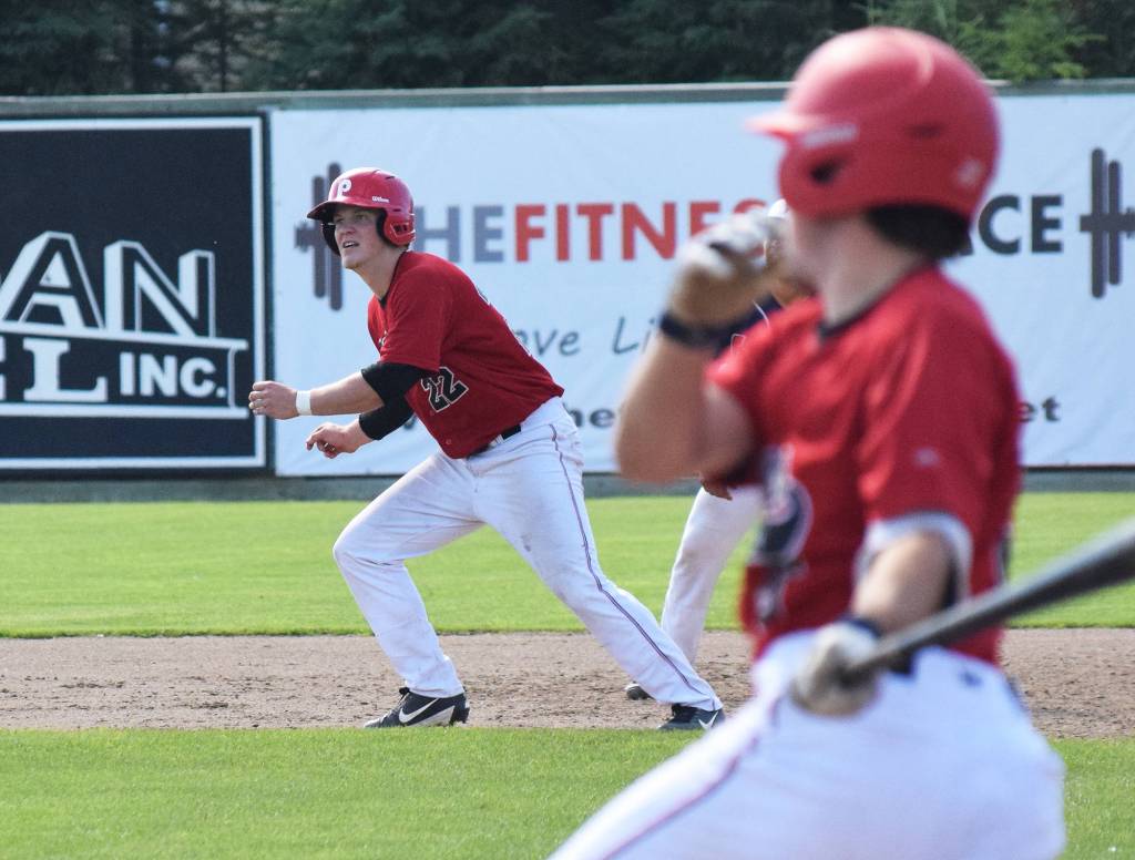 Kellen Strahm (22) watches as Peninsula Oilers teammate Paul Kunst hits a double against the Chugiak Chinooks Saturday afternoon at Coral Seymour Memorial Ballpark in Kenai. (Photo by Joey Klecka/Peninsula Clarion)