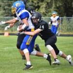 Nikiski senior Tyler Olson (14) tackles Monroe Catholic running back Isaac Garcia in the first half Saturday at Nikiski High School. (Photo by Joey Klecka/Peninsula Clarion)