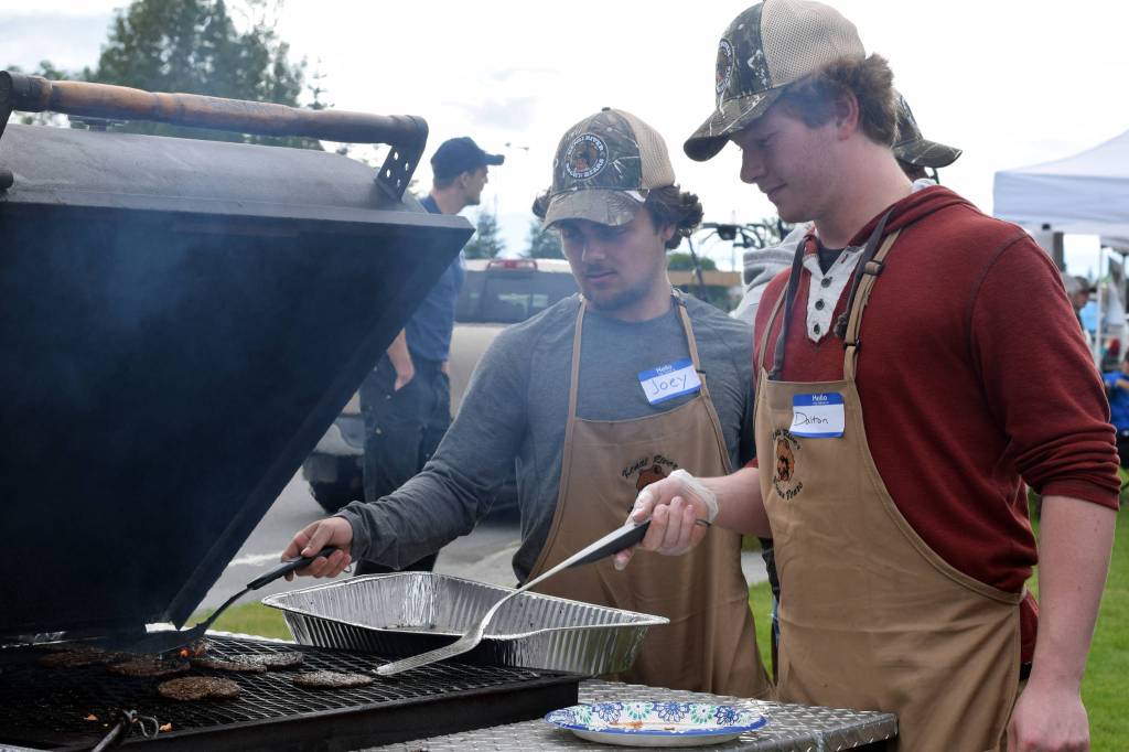 Joey Allegrini, left, and Dalton Dosko of the Kenai River Brown Bears ice hockey team help serve food during Industry Appreciation Day on Saturday, Aug. 26 in Kenai. (Photo by Kat Sorensen/Peninsula Clarion)