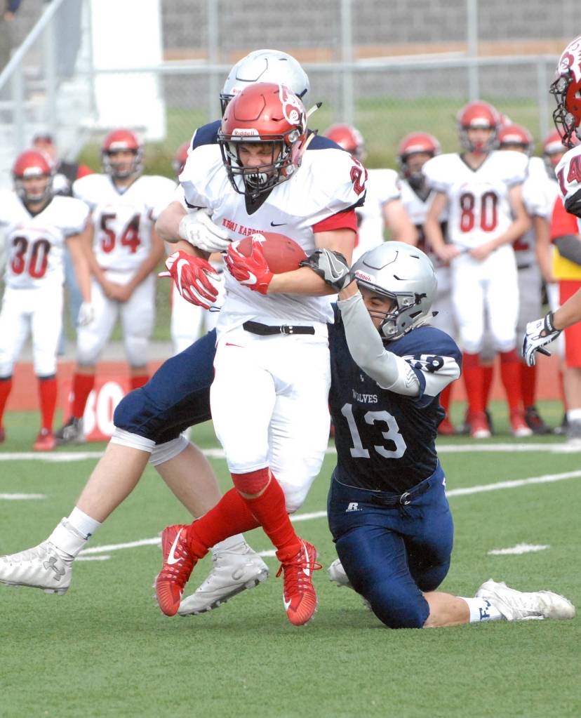 Kenai&rsquo;s Titus Riddall is tackled by Eagle River&rsquo;s JT Adams, right, and Bryson Rollman during the Kardinals&rsquo; 42-28 Northern Lights Conference football win over the Wolves on Saturday, Sept. 2, 2017 at Eagle River High School. (Star photo by Matt Tunseth)