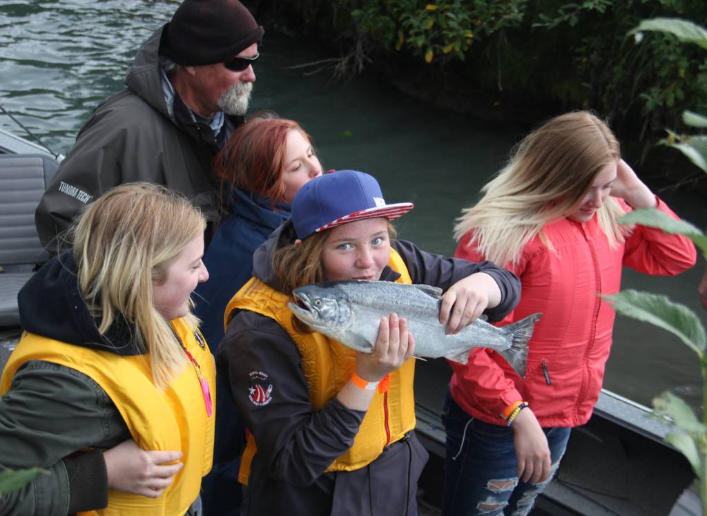 A young angler kisses her first silver salmon for luck.