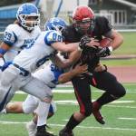 Kenai Central senior Seth Kruse (right) attempts to escape a tackle by Palmer defenders Patrick Dickens (88) and Levi Farris, Saturday at Ed Hollier field in Kenai. (Photo by Joey Klecka/Peninsula Clarion)