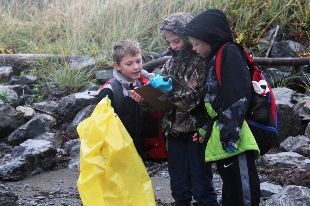 Niko Erickson (left), Tanner Johnson (center) and Zephaniah Weisser (right) look at the progress they&rsquo;ve made in recording their findings on the shoreline of Kachemak Bay on Friday, Sept. 22, 2017 near Mariner Park in Homer, Alaska. Several classes from McNeil Canyon Elementary School participated in this year&rsquo;s Kachemak Bay CoastWalk, in which students and citizen groups can adopt a section of coast to clean up. (Photo by Megan Pacer/Homer News)